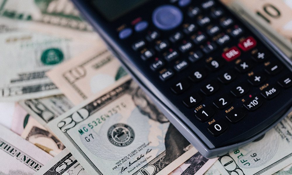 Blog - Calculator Sitting on a Pile of 20 Dollar and 10 Dollar Bills